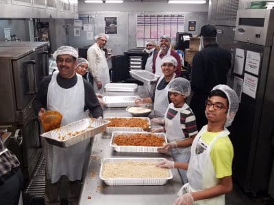 Volunteers preparing and serving food in a busy kitchen.