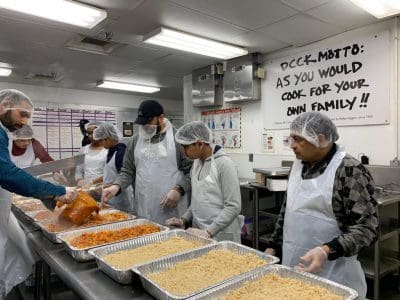 Volunteers prepare meals in a busy kitchen.
