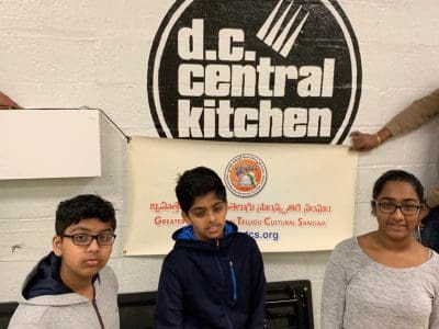 Three children standing in front of a d.c. central kitchen sign.