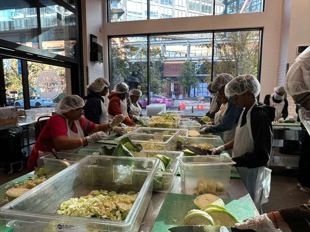 People in hairnets chopping cabbage together