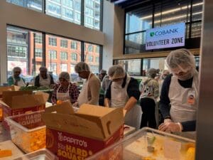 Volunteers wearing hairnets packing food boxes